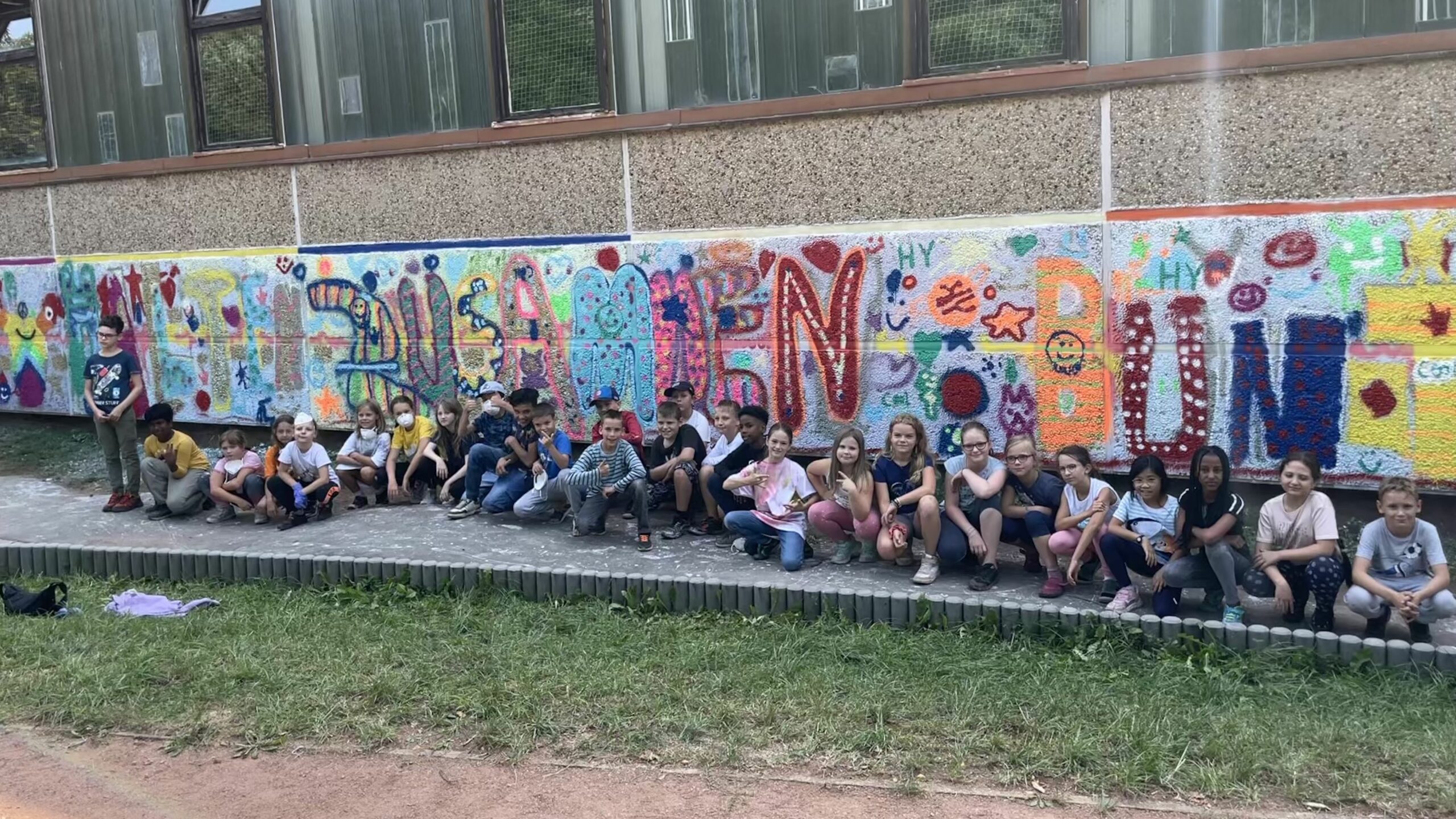 Vierte Klassen der 19. Grundschule vor dem Fertigen Slogan "Wir halten zusammen, bunt gemischt". Foto: Charlotte Otto