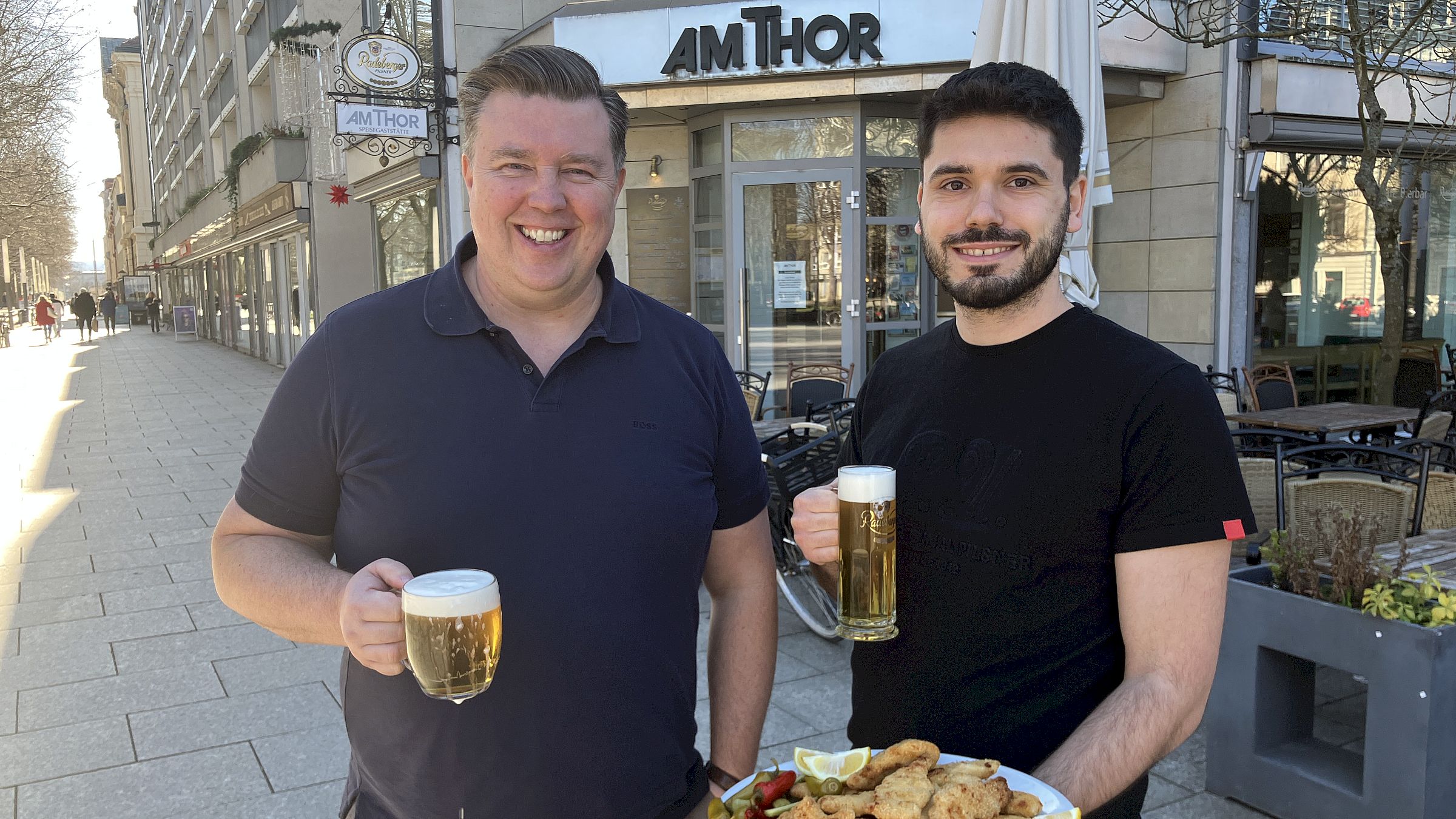 Josef Míček (li.) mit Betriebsleiter Benjamin Sadiki und einer Schnitzelei-Auswahl vor dem „Babička am Thor“ auf der Hauptstraße - Foto: meeco Communication Services